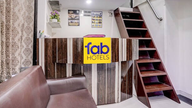 Una recepción con un letrero de 'fab hotels', una escalera y un reloj en la pared.