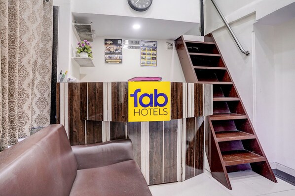 Ein Empfangstresen mit einem 'fab hotels' Schild, eine Treppe und eine Uhr an der Wand.