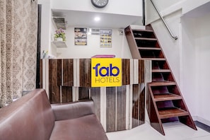 Ein Empfangstresen mit einem 'fab hotels' Schild, eine Treppe und eine Uhr an der Wand.