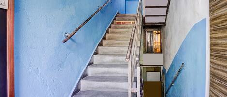A staircase with blue walls and metal handrails, leading to a room with a window.