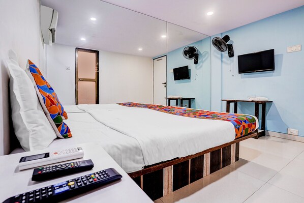A hotel room with a bed, a TV, a mirror, and a small table. - Fabhotel Blue Light (Mumbai)