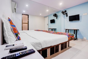 Ein Hotelzimmer mit Bett, Fernseher, Spiegel und einem kleinen Tisch.