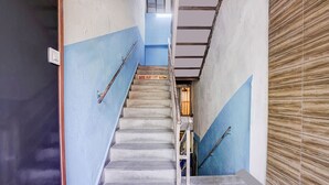 A staircase with a handrail, a sign indicating the second floor, and a wooden panel wall. - Fabhotel Blue Light (Mumbai)