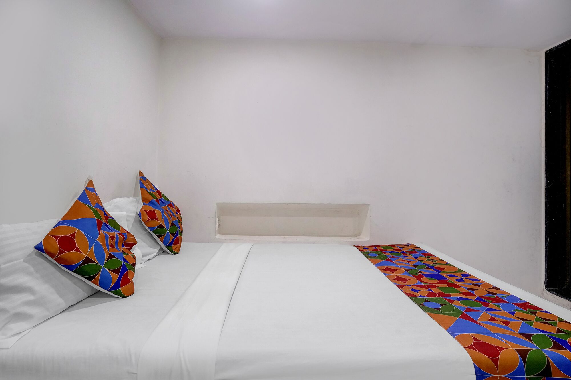 A bedroom with a bed, pillows, and a patterned runner.