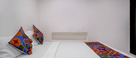 A bedroom with a bed, pillows, and a patterned runner.