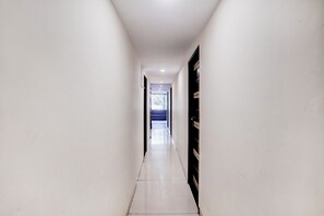 A narrow, well-lit hallway with a tiled floor and white walls.