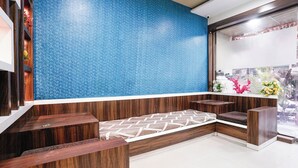 A reception area with a blue textured wall, wooden benches, and a tiled floor. - Fabhotel Aarvi Inn (Chhatrapati Sambhajinagar)