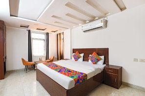 A hotel room with a bed, a desk, a chair, an air conditioning unit, and a window. - FabHotel The Royal Residency - Dashrathpuri Metro (New Delhi)