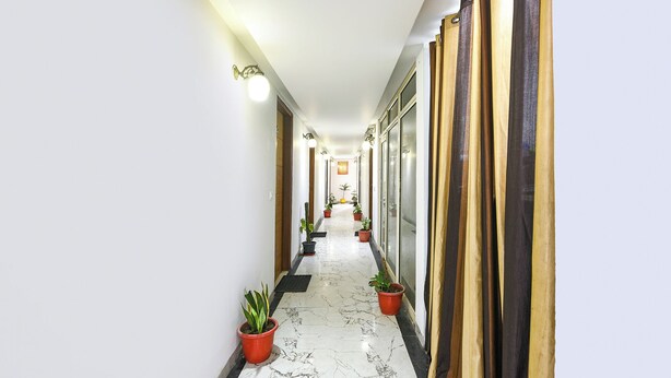 A hallway with potted plants, a marble floor, and a wooden door at the end. - FabHotel The Royal Residency - Dashrathpuri Metro (New Delhi)