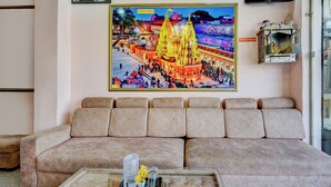 A living room with a sofa, a glass coffee table, and a framed picture of a temple on the wall. - FabHotel Chandra Dreams - 600m from Banaras Railway Station (Varanasi)