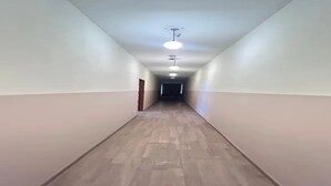 En lång, smal hall med trägolv och vita väggar.