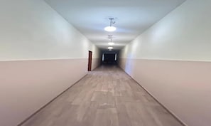 Pitkä, kapea käytävä, jossa on puulattia ja valkoiset seinät.