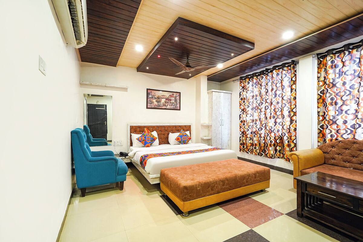 Una habitación de hotel con cama, sofá, sillón, escritorio y ventilador de techo.