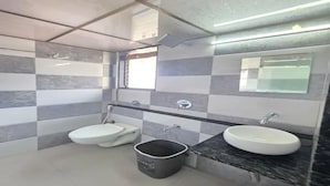 A bathroom with a toilet, bidet, sink, and a trash bin. - Fabhotel Rs Regency (Mumbai)