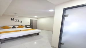 A hotel room with a bed, a door, and a ceiling fan. - Fabhotel Rs Regency (Mumbai)