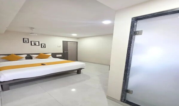 A hotel room with a bed, a door, and a ceiling fan.