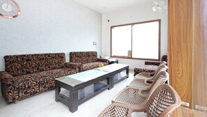 A living room with patterned sofas, a glass-top coffee table, and wicker chairs. - FabHotel The Dayals & Lawns - Nr. Ayodhya Dham Bus Station (Faizabad)