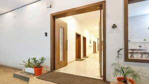 A hallway with wooden doors, potted plants, and a mirror on the wall. - FabHotel The Dayals & Lawns - Nr. Ayodhya Dham Bus Station (Faizabad)
