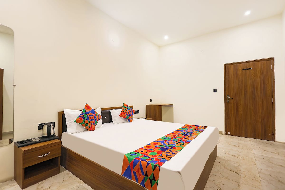 A bedroom with a bed, bedside tables, a wooden wardrobe, a mirror, and a door.