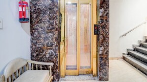 An elevator with a marble wall, a fire extinguisher, and a staircase. - FabHotel Casa Royal - Greater Kailash (New Delhi)