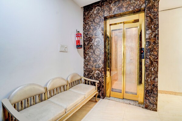 Una habitación con un sofá, un extintor de pared y una puerta con pantalla digital.