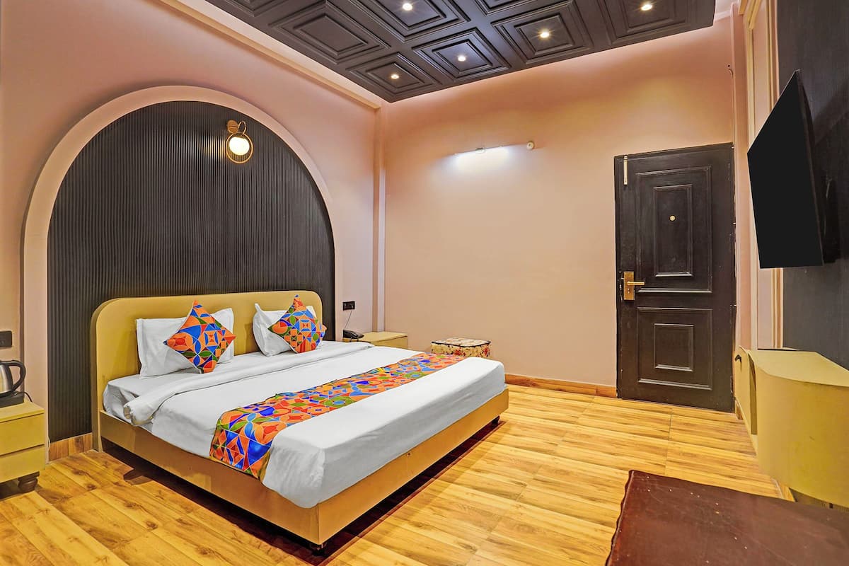 A bedroom with a bed, a bedside table, a nightstand, a door, and a ceiling light fixture.
