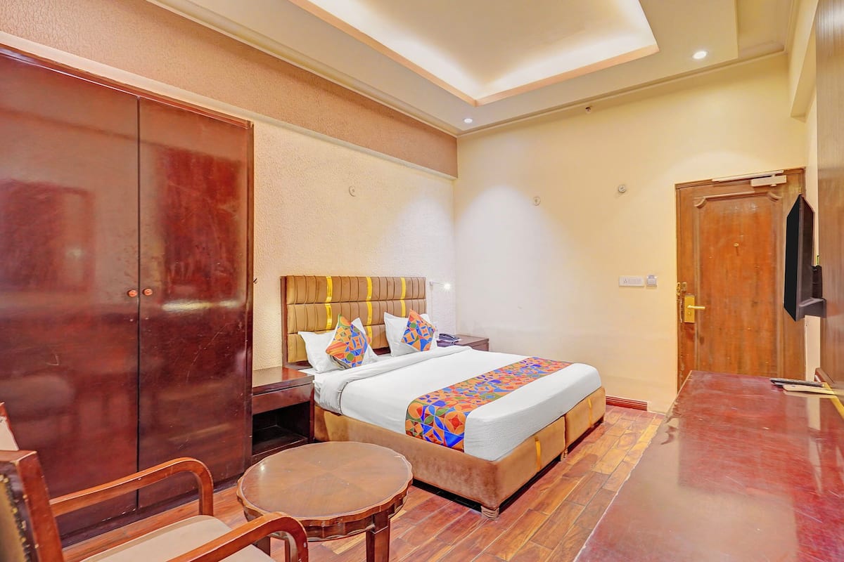A hotel room with a bed, a wooden chair, a small round table, and a wardrobe.