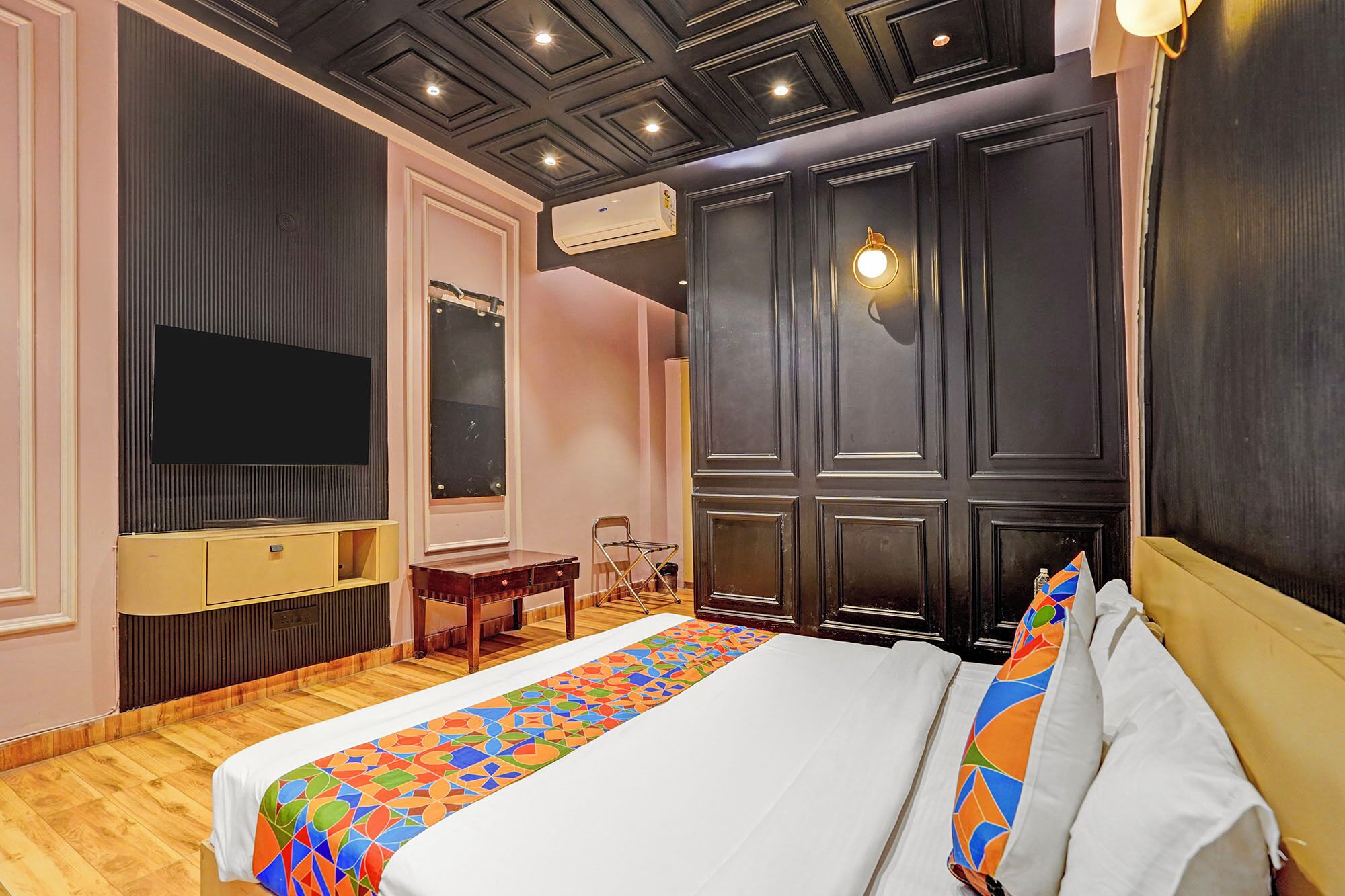 Een hotelkamer met een bed, een televisie, een bureau en een kledingkast.