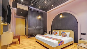 A hotel room with a bed, bedside table, and a desk with a chair.