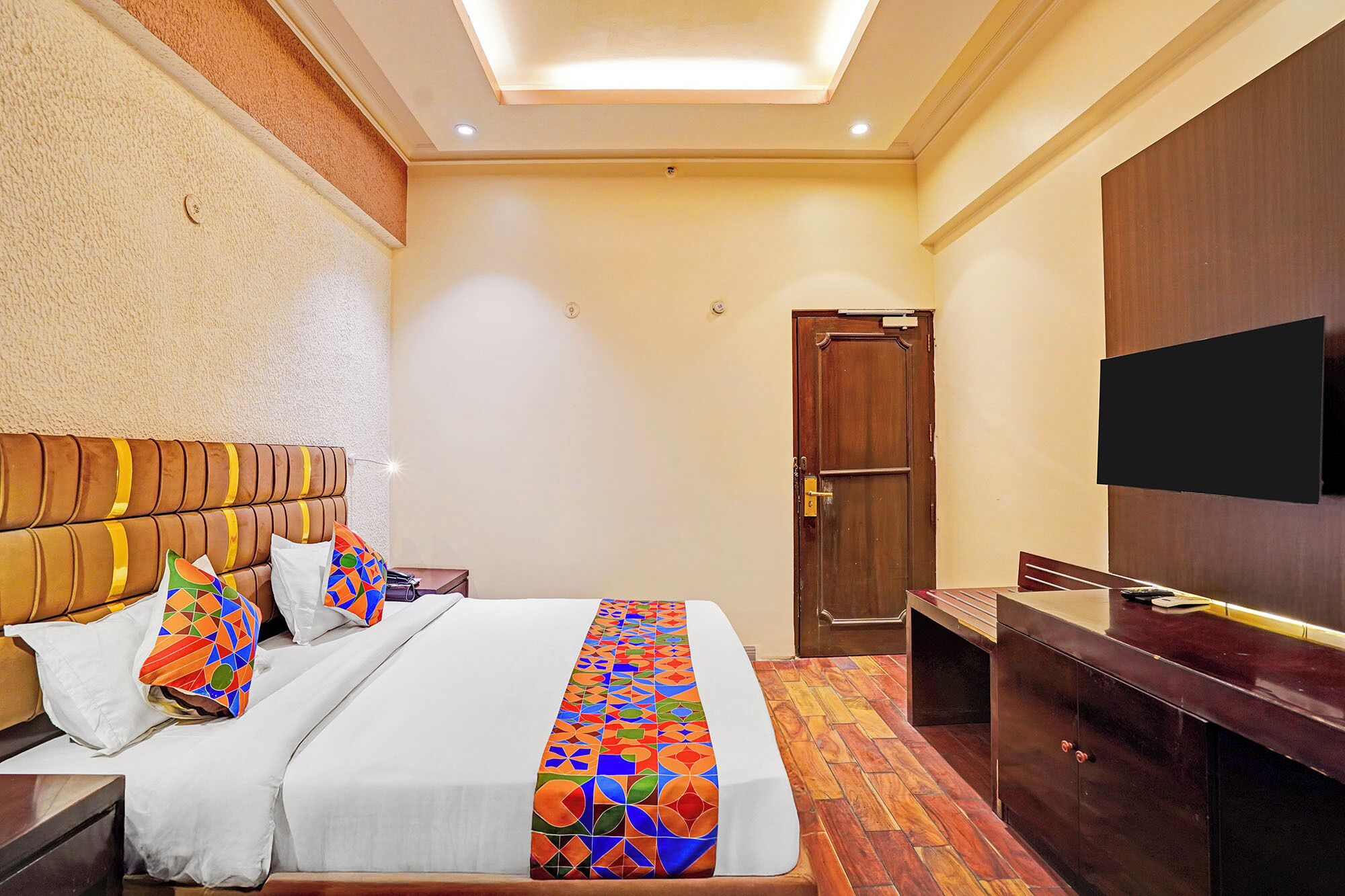 A hotel room with a bed, a TV, a wardrobe, and a door.