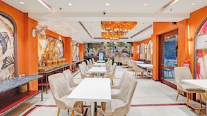 A restaurant with a long counter, multiple tables, and chairs.