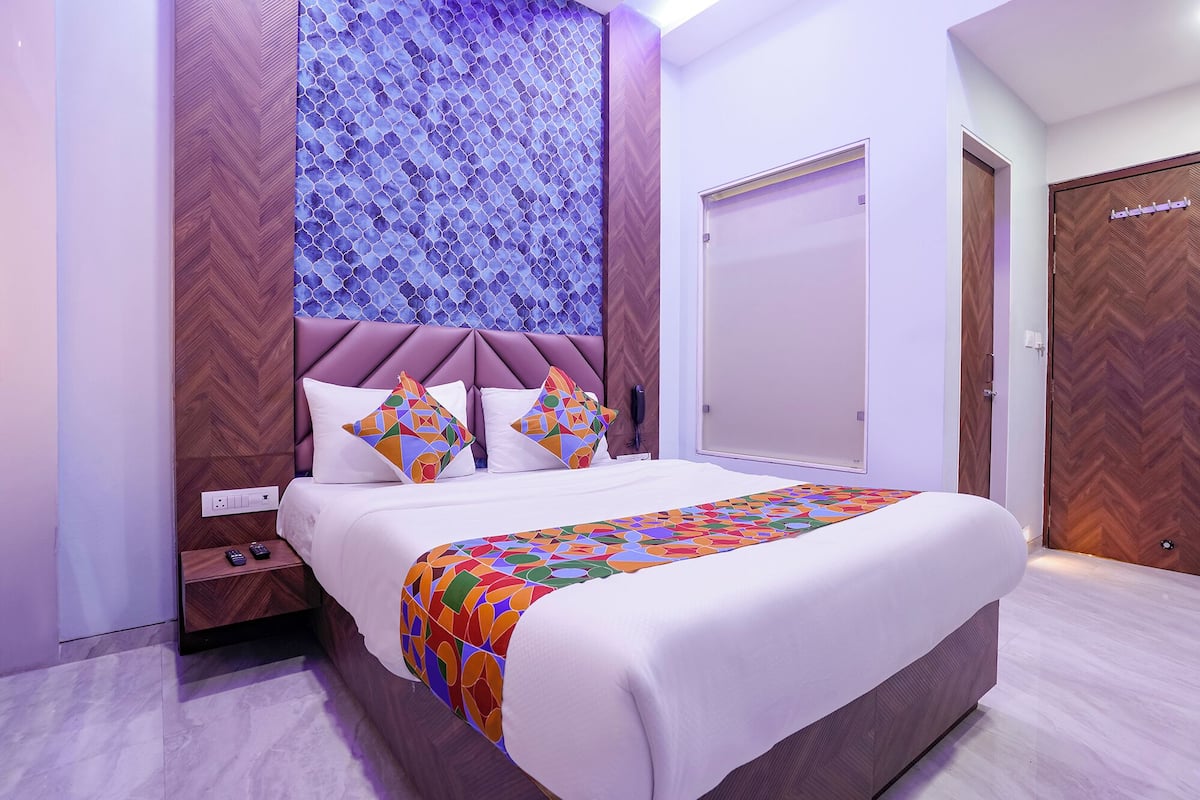 Une chambre moderne avec un grand lit, un mur orné d’un motif en chevrons et une porte en bois.