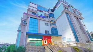 A multi-story building with a prominent entrance, a staircase leading to the entrance, and a sign indicating it is a hotel. - Fabhotel Arc Homes (Bhubaneshwar)