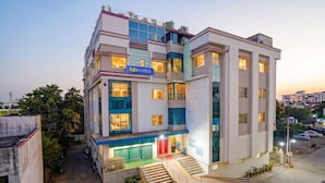 A multi-story hotel with a sign reading 'fabHOTELS,' a staircase, and a parking area. - Fabhotel Arc Homes (Bhubaneshwar)