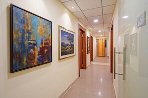 A hotel corridor with framed artwork on the walls, wooden doors, and a tiled floor. - Fabhotel Arc Homes (Bhubaneshwar)