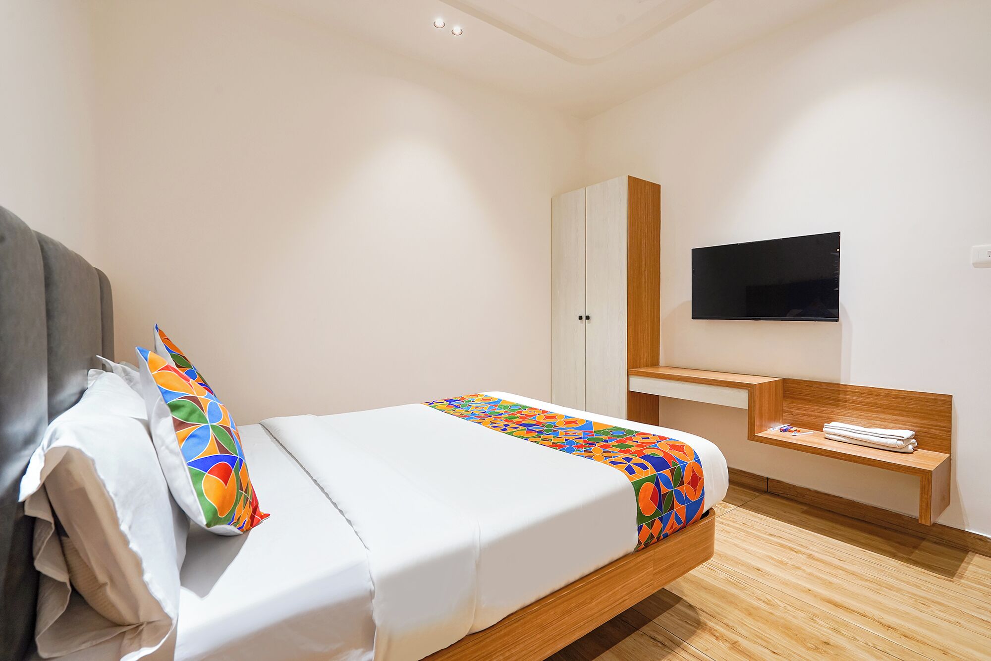 Een hotelkamer met een bed, een televisie, een houten bureau en een kledingkast.