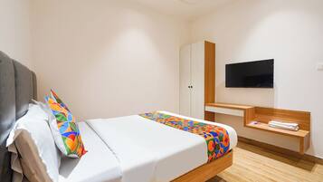 Een hotelkamer met een bed, een televisie, een houten bureau en een kledingkast.