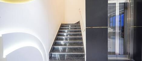 A modern staircase leading to a glass door entrance.