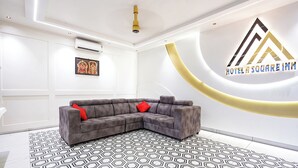 Eine moderne Hotelhalle mit einer grauen Eckcouch, einem gemusterten Boden und einer Wand-Klimaanlage.