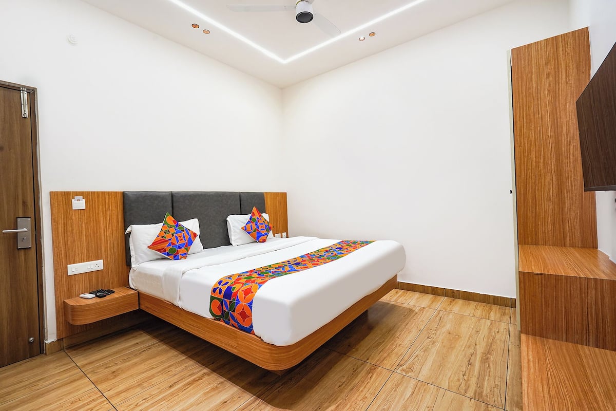Un dormitorio moderno con cama, cabecero de madera, mesitas de noche y un armario.