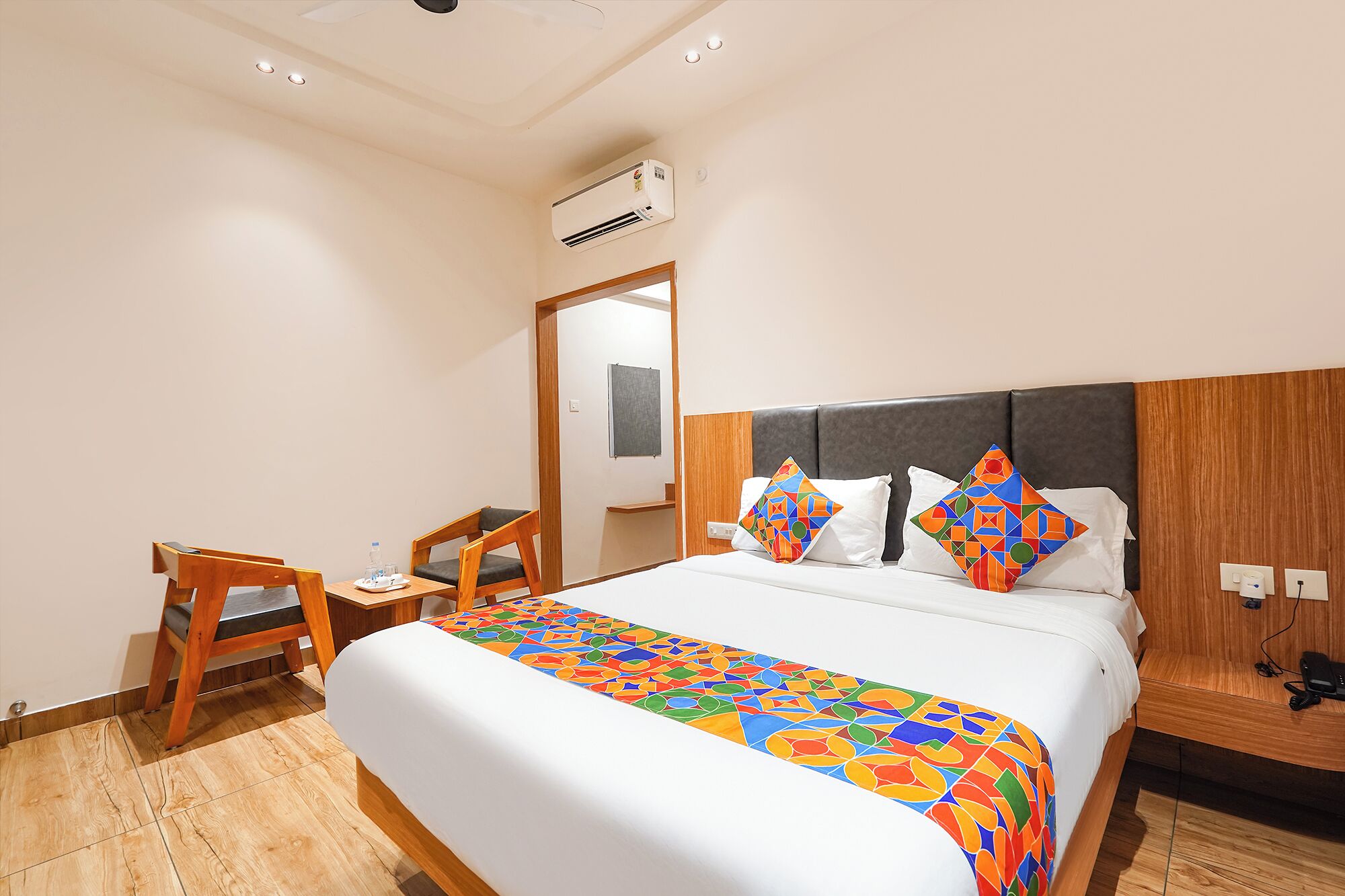 Una habitación de hotel con cama, escritorio, silla y aire acondicionado.