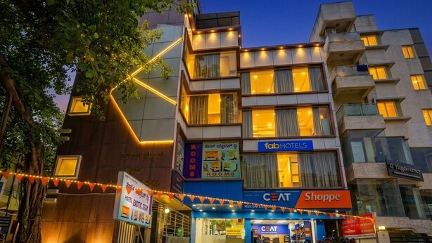 A multi-story building with a ground-level shop, a hotel named 'Fab Hotels,' and a sign for 'Rooms.' - FabHotel Exotic Stay - Kalyan Nagar (Bangalore)
