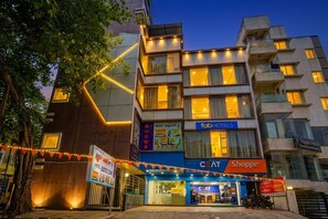 A multi-story building with a ground-level shop, a hotel named 'Fab Hotels,' and a sign for 'Rooms.' - FabHotel Exotic Stay - Kalyan Nagar (Bangalore)