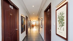 A hallway with wooden doors, numbered 106, and framed botanical illustrations on the walls. - FabHotel Exotic Stay - Kalyan Nagar (Bangalore)