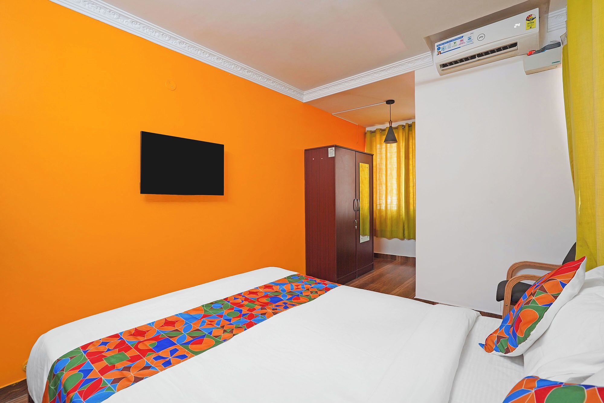 Camera d'albergo con un letto, un armadio, un condizionatore d'aria e una finestra con tende.