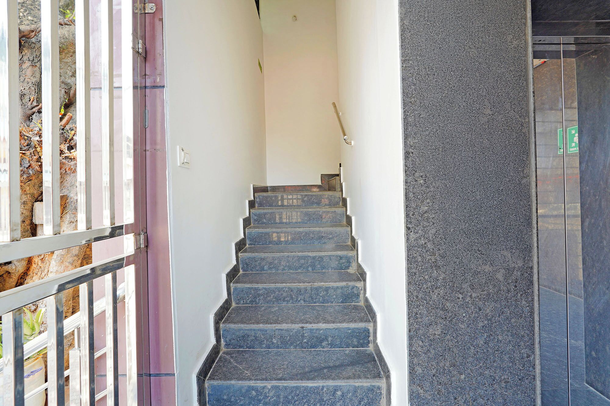 A staircase leading to a landing with a metal railing on one side and a textured wall on the other.