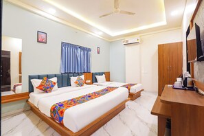 A hotel room with a bed, bedside tables, a desk, a wardrobe, a ceiling fan, and an air conditioning unit.