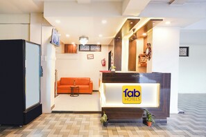 A reception area with a reception desk, a sofa, a television, and a fire extinguisher.