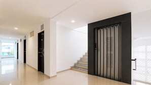 A modern interior with a staircase, a black door with a digital lock, and a hallway with a glass door. - Fabhotel Rvc Hospitality (Pune)