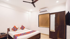 A hotel room with a bed, bedside table, nightstand, wardrobe, and a ceiling fan. - Fabhotel Rvc Hospitality (Pune)